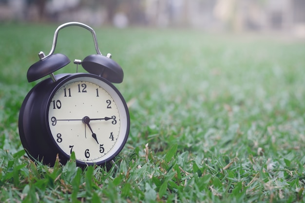 Photo black alarm clock on grass background