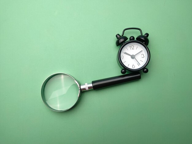 Black alarm clock and magnifying glass