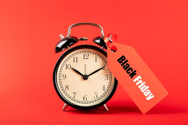 Black alarm clock on a red background with the inscription BLACK FRIDAY. SHOP TIME. Black Friday con