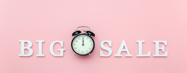 black alarm clock and text big sale from white volume letters on pink 