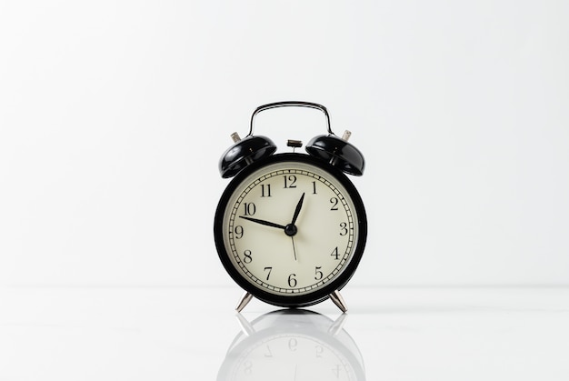 Black alarm clock on white table.