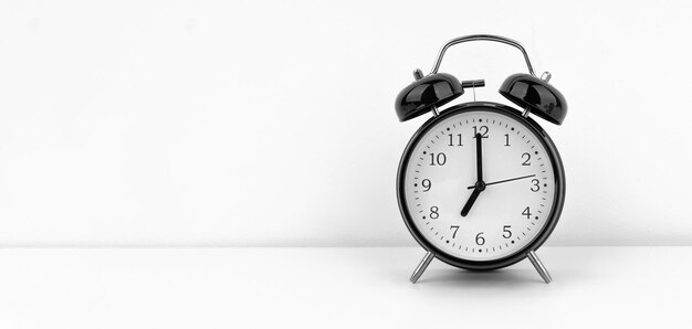 Black alarm clock on white wall background