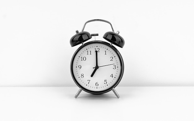 Photo black alarm clock on white wall background