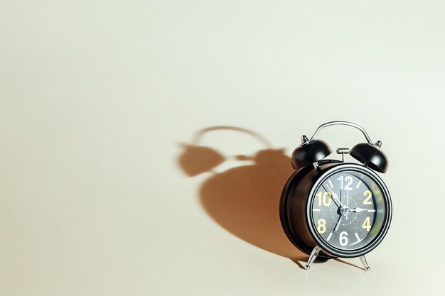 Black alarm clock with dial on beige background Concept of time and timing with space for copying