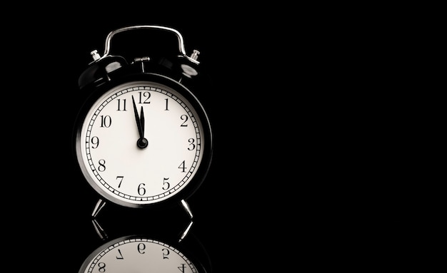 black alarm clock with reflect on black background and copy space.