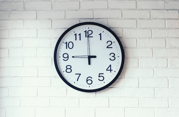 写真 白いレンガの壁の背景に黒と白の時計。時計に、時計に9。