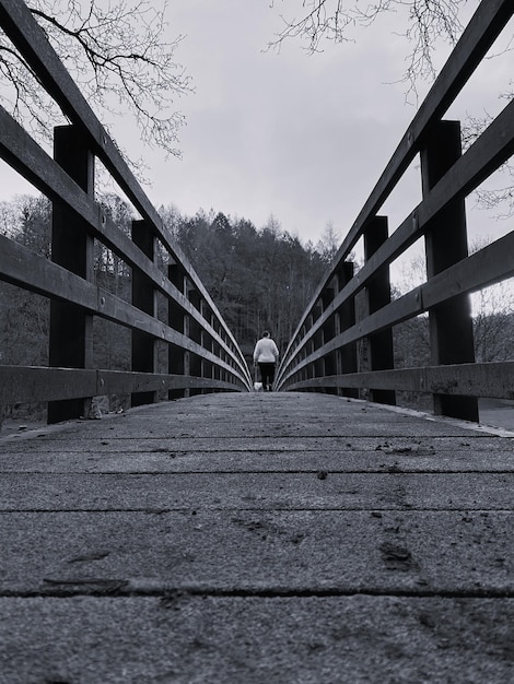 Фото Черно-белый монохромный задний вид женщины, идущей по деревянному мосту