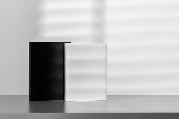 사진 그림자 와 함께 회색 배경 에 대 한 회색 책상 에 서 있는 검은색 과 색 노트 패드