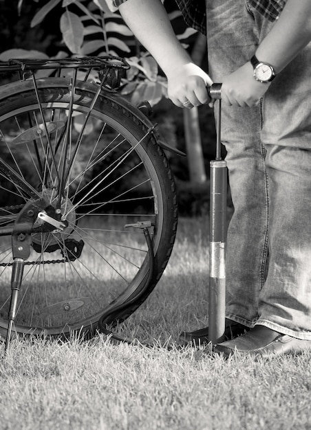 写真 手動ポンプで自転車のタイヤをポンピングする若い男の白黒写真