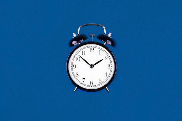 Black antique alarm clock on trendy Classic Blue