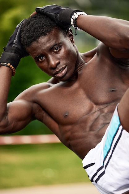 A black athlete doing abdominal exercises an African American athlete exercising in a park on a playground in a proud environment