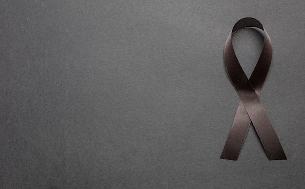 Black awareness ribbon on black color background Melanoma and sorrow concept