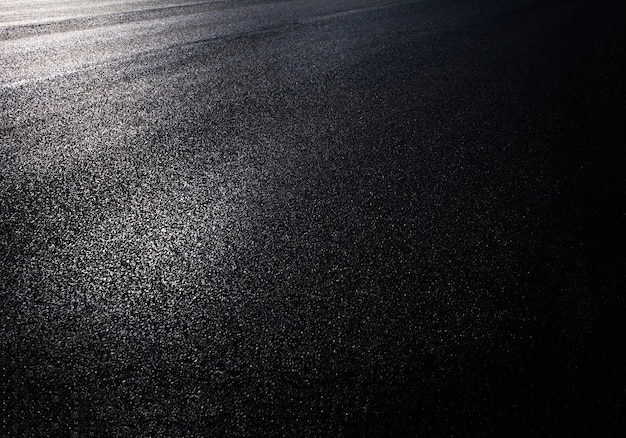 A black background asphalt surface with a white light on it