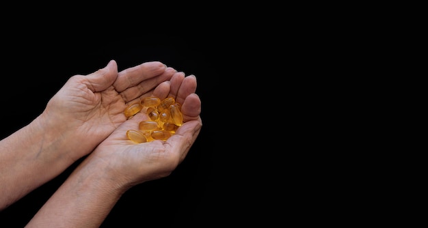 Black background In the hands of an elderly woman different types of medicines