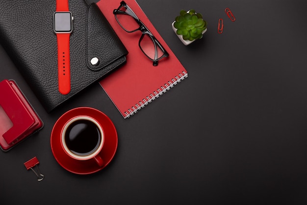 黒の背景赤コーヒーカップメモ帳目覚まし時計花日記スコアテーブルの上のキーボード。コピースペース平面図