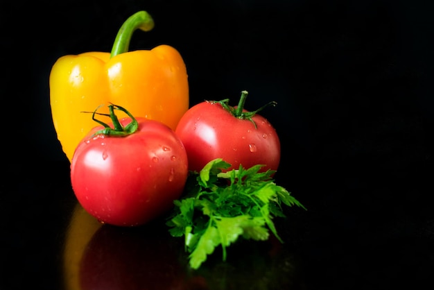 A black background with tomatoes and a green leafy vegetable.