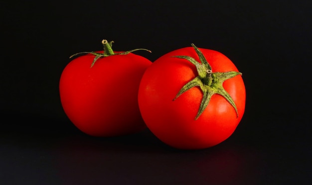 A black background with two tomatoes on it