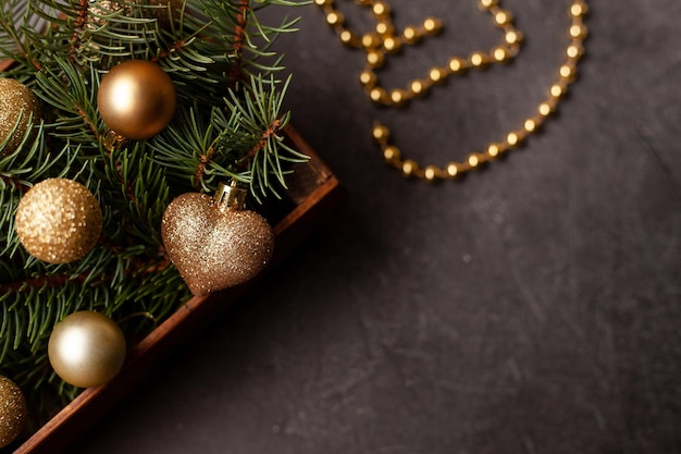 Black background with wooden box of golden Christmas balls