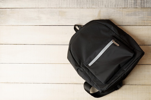 Black backpack on white wooden table with copy space for text