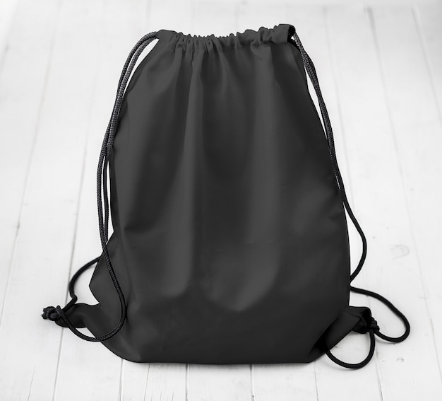 Photo black backpack with strings on planked surface