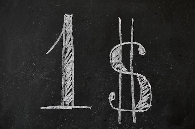 На черной изношенной доске крупными буквами написано число один и знак доллара