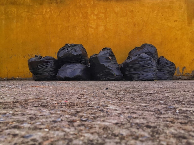 Black bag garbage dump beside the wall