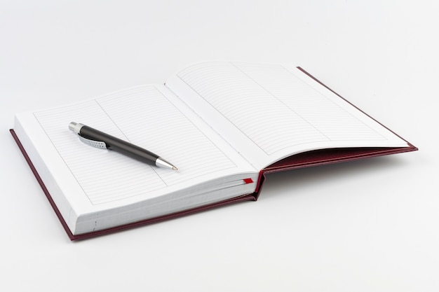 Black ballpoint pen on open diary on white background