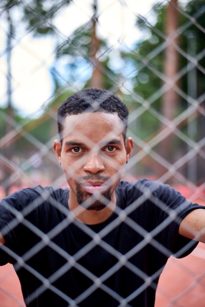 Black basketball player holding the chain link fence with hands