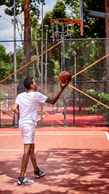 Giocatore di pallacanestro nero che tiene il recinto del collegamento a catena con le mani