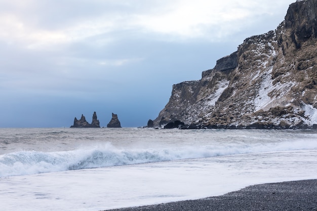 Black beach rocks and waves near the Vik during the winter sunset