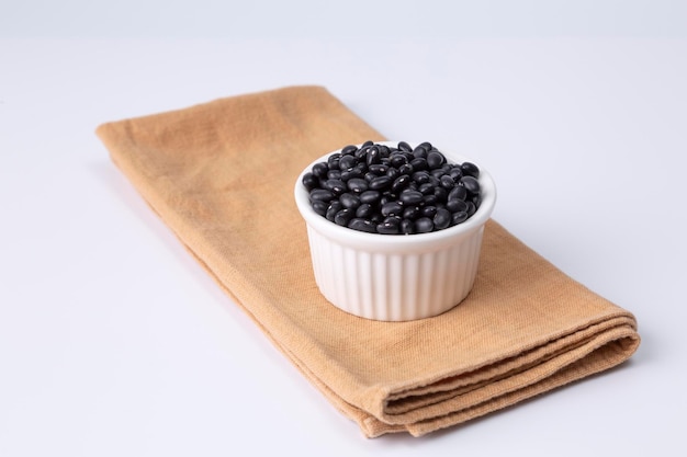 Black bean in white bowl on cloth and white background studio shot