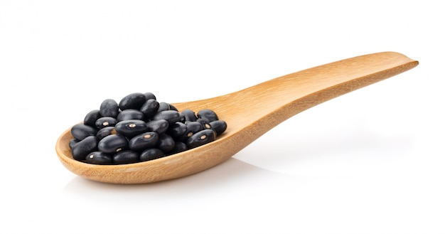 Black beans in wood spoon isolated on white