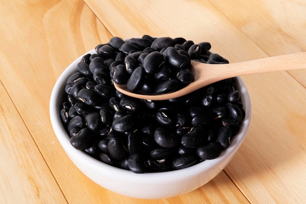 Black Beans in wooden spoon with ceramic bowl