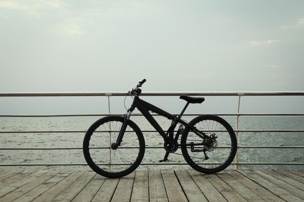 black bicycle on wooden floor outdoors by the sea