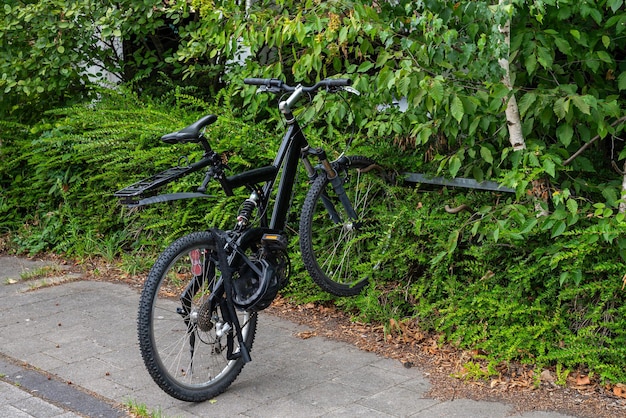 Black bike parked on the edge of the footpath