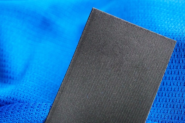 Черная пустая этикетка для ухода за прачечной на фоне спортивной рубашки из синего джерси из полиэстера