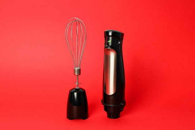 Black blender with whisk on red background