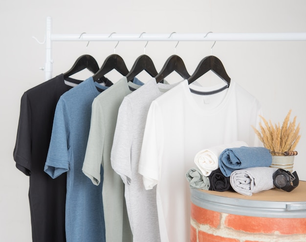 Black,blue, grey and white t-shirts on hangers on gray background