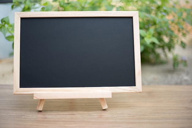 Photo black board on wood table top with sun and blur green tree bokeh background, template mock up for d