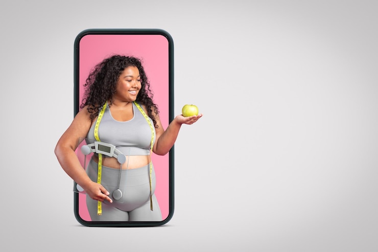 Photo black body positive woman in sportswear holding apple and scales standing on big smartphone screen