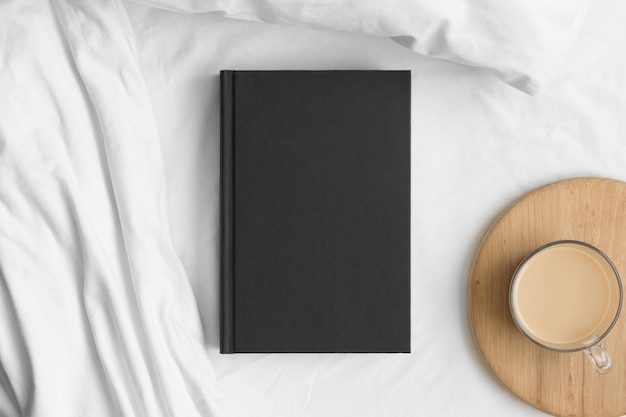 Макет черной книги с чашкой кофе на кровати