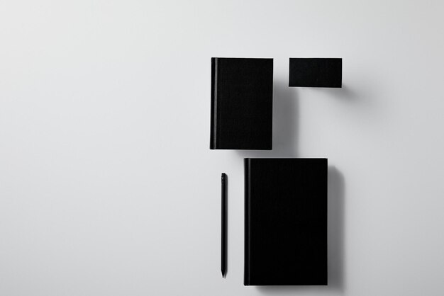 Foto libro nero, taccuino e penna nera isolati su sfondo bianco.