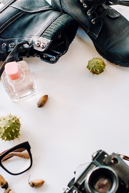 Black boots lie with the camera, glasses and acorns.