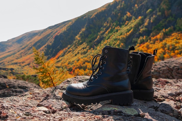 写真 山の背景に黒いブーツ。ツーリストブーツ。背景の山。