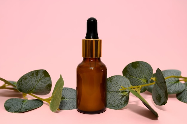 Black bottle of lotion with green eucalyptus branches On a pink background Closeup