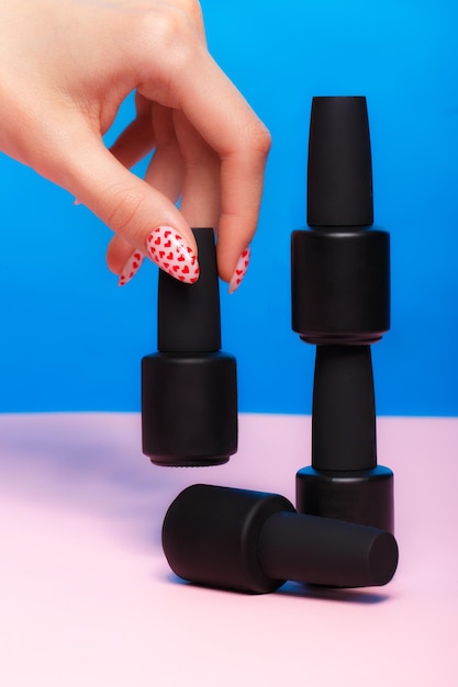 Black bottles of nail polish on a colorful background Manicure design