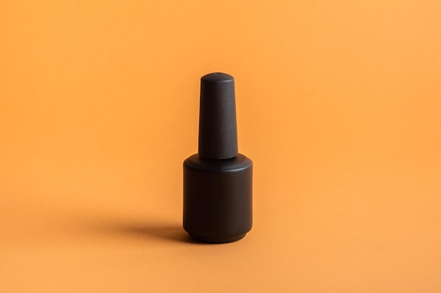 Black bottles of nail polish on an orange background