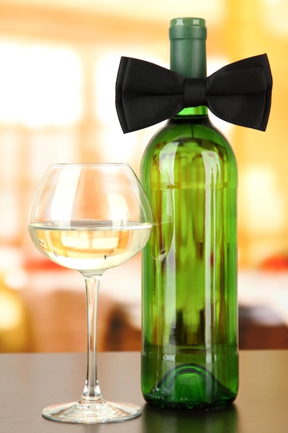 Black bow tie on wine bottle on bright background