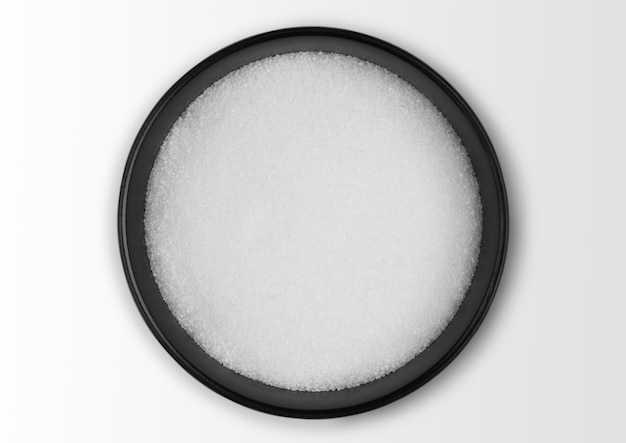 Black bowl of natural white refined sugar on white Top view