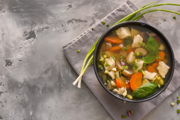 Black bowl with delicious turkey soup on grey table